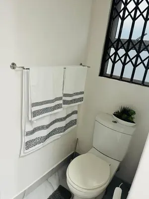 a white bathroom with a toilet and a towel at Self catering one bedroom cottage in Cape Town