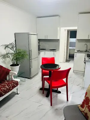 a kitchen with red chairs and a table in a room at Self catering one bedroom cottage in Cape Town