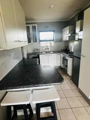 a kitchen with white cabinets and a black counter top at Boho Bliss in Cape Town