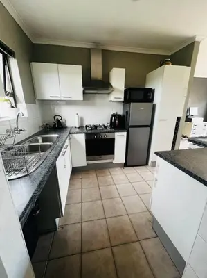 a small kitchen with white cabinets and appliances at Boho Bliss in Cape Town