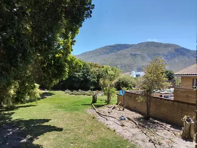 a yard with a fence and a mountain in the background at Rustig by die See in Bettyʼs Bay