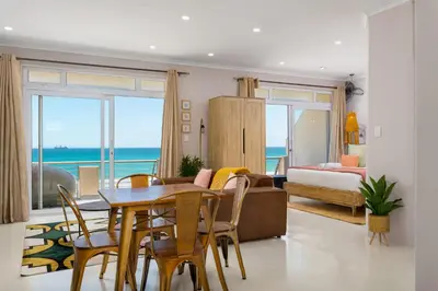 a living room with a table and chairs and a bedroom at 323 Leisure Bay in Cape Town