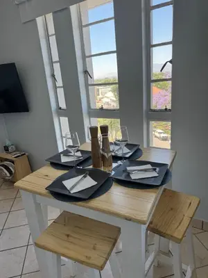 a dining room table with two chairs and two windows at Windpomp Self Catering in Paarl