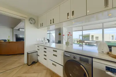 a large kitchen with a washer and dryer in it at Dolphin beach Apartment -Kite beach in Cape Town