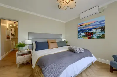 a bedroom with a bed and a painting on the wall at Dolphin beach Apartment -Kite beach in Cape Town