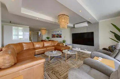 a living room with leather furniture and a flat screen tv at Dolphin beach Apartment -Kite beach in Cape Town