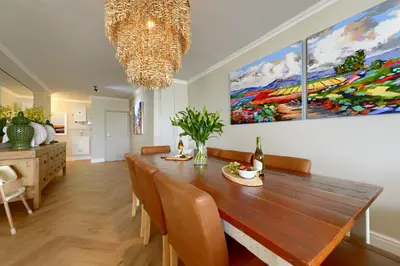 a dining room with a table and a painting on the wall at Dolphin beach Apartment -Kite beach in Cape Town