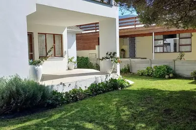 a white house with a yard with a grass yard at Mogit-ewig-duur in Hermanus