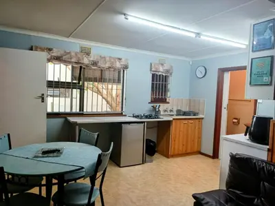 a kitchen with a table and a kitchen with a table and chairs at LAAT Slaap Self-Catering Accommodation in Kleinmond
