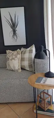 a living room with a couch with a pillow and a table at V's Condo in Gordonʼs Bay