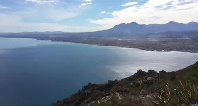 a view of a large body of water with mountains at V's Condo in Gordonʼs Bay