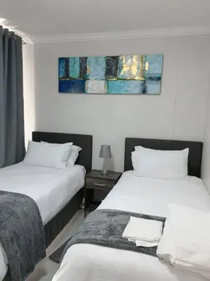 a bedroom with two beds and a painting on the wall at 107 St Tropez Eyrie Holiday Apartments in Cape Town