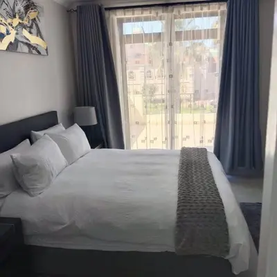 a bedroom with a bed and a large window at 107 St Tropez Eyrie Holiday Apartments in Cape Town