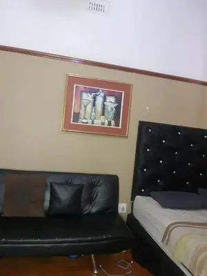 a bedroom with a bed and a black leather couch at Room Parow, Cape Town in Cape Town
