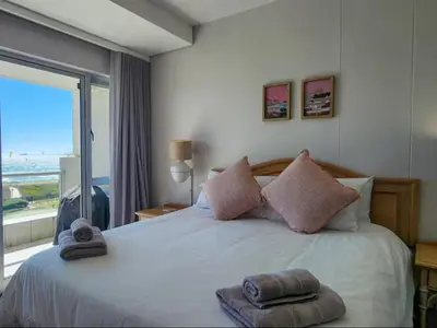 a bedroom with a large bed with a large window at Dolphin Delight in Bloubergstrand