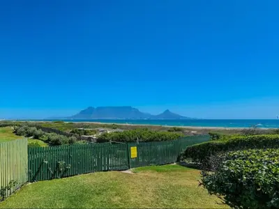 a fence with the ocean in the background at Dolphin Delight in Bloubergstrand