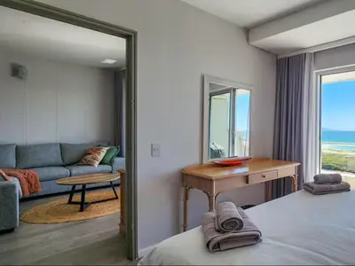 a room with a bed and a couch and a mirror at Dolphin Delight in Bloubergstrand