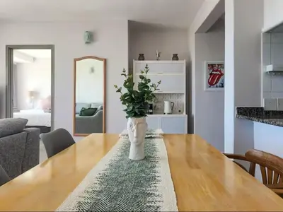 a dining room table with a vase with a plant on it at Dolphin Delight in Bloubergstrand