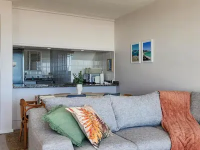 a living room with a couch and a kitchen at Dolphin Delight in Bloubergstrand