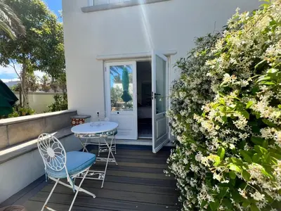 a balcony with a table and chairs and flowers at Charming Flatlet Near the Amazing Sunset Beach in Cape Town