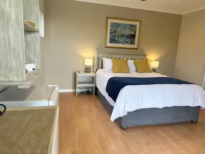 a bedroom with a large bed with yellow pillows at Lily's Lodge in Somerset West