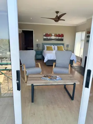 a bedroom with a bed and two chairs and a table at Lily's Lodge in Somerset West
