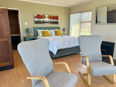 a bedroom with a bed and two chairs at Lily's Lodge in Somerset West