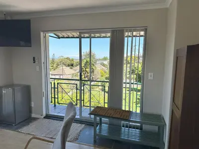 a living room with a view of a balcony at Lily's Lodge in Somerset West
