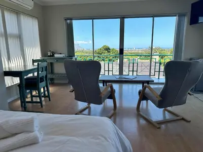 a bedroom with a bed and two chairs and a table at Lily's Lodge in Somerset West