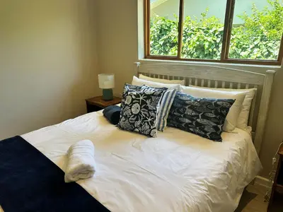 a bedroom with a bed with pillows and a window at Lily's Lodge in Somerset West