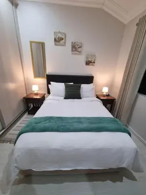 a bedroom with a large bed with a green blanket at A cozy retreat - feels like home in Cape Town