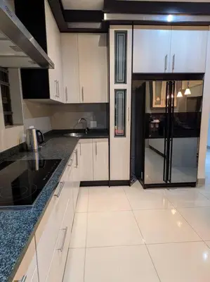 a kitchen with white cabinets and a black refrigerator at A cozy retreat - feels like home in Cape Town