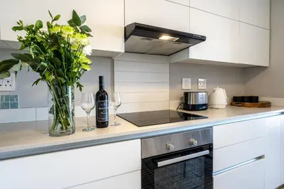 a kitchen with a vase of flowers and wine glasses at Top Floor Beachfront w Views, Blouberg, 51 Beach Break in Bloubergstrand