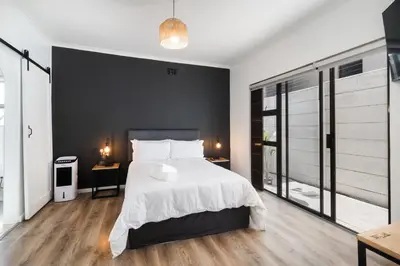 a bedroom with a large bed and a black wall at En-suite Room, Walking distance to Kite Beach in Cape Town