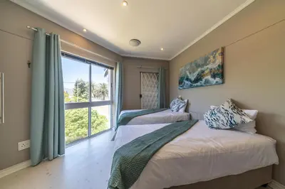 two beds in a room with a large window at 4 Serene Palms in Cape Town