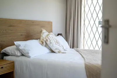 a bedroom with a bed with white pillows and a window at 4 Serene Palms in Cape Town
