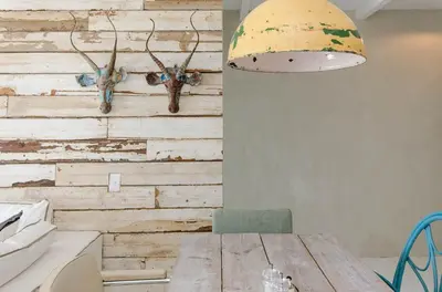 a dining room with a wooden table with antlers on a wall at Dolphin Hill Apartment, Cape Town, Dolphin Beach in Cape Town