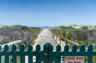 a boardwalk on the beach with a sign on it at Dolphin Hill Apartment, Cape Town, Dolphin Beach in Cape Town