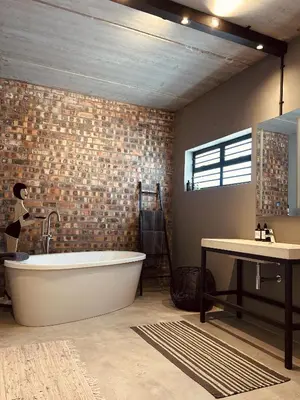 a bathroom with a large tub and a sink at Tether and Tease, The Citadel in Cape Town