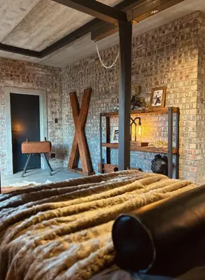 a bedroom with a bed and a brick wall at Tether and Tease, The Citadel in Cape Town