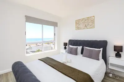 a bedroom with a large bed with a window at Wake Up to the Waves - Portico in Cape Town