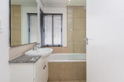 a bathroom with a sink and a tub and a mirror at Wake Up to the Waves - Portico in Cape Town