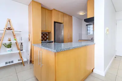 a kitchen with wooden cabinets and a counter top at Wake Up to the Waves - Portico in Cape Town