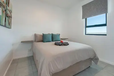 a bedroom with a large bed with a window at Perlemoen Apartments in Hermanus