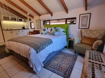 a bedroom with a bed and a couch and a chair at The Sculpture Yard in Gordonʼs Bay