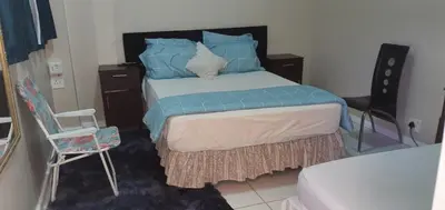 a bedroom with a bed with blue pillows and a chair at Skyway Sleep and go in Cape Town