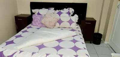 a bed with purple and white pillows on it at Skyway Sleep and go in Cape Town