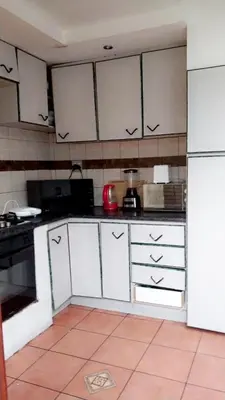 a kitchen with white cabinets and a red appliance at Hussein accommodation in Cape Town