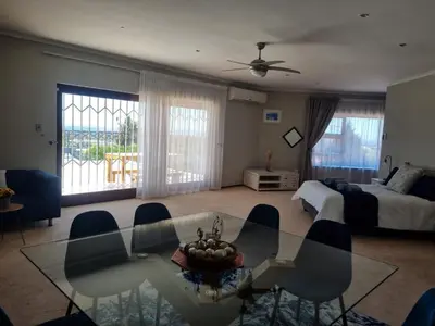 a living room with a bed and a glass table and chairs at Grace Space in Plattekloof in Cape Town