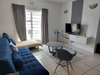 a living room with a blue couch and a tv at Azzure Apartments 3 sleeper Strand in Strand